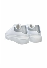 Białe sneakersy z gładkim materiałowym wierzchem, srebrnym akcentem na pięcie i grubą białą gumową podeszwą. Posiadają okrągłe sznurówki i proste przeszycia.