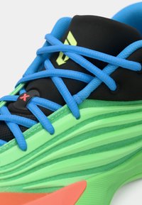 Green and black athletic shoe with blue laces, featuring a textured black upper, sleek green midsole, and an orange accent on the side.