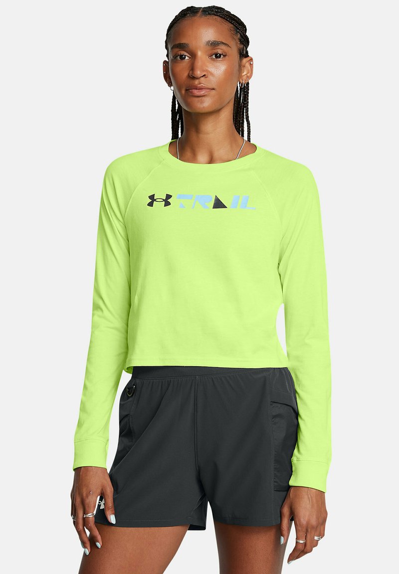 Neon-grünes, kurzes Langarmshirt mit blauem und schwarzem "TRAIL"-Grafikdesign; kombiniert mit schwarzen Sportshorts mit seitlichen Taschen.