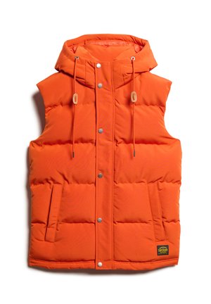 Orange padded vest with a hood, snap buttons, two side pockets, and adjustable drawstrings. Features a textured finish and logo patch.