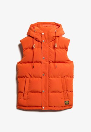 Gilet rembourré orange avec capuche, boutons-pression, deux poches latérales et cordons de serrage ajustables. Présente une finition texturée et un patch logo.