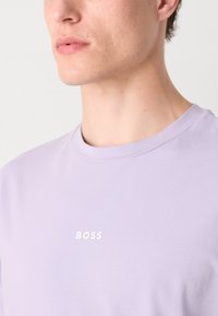 Hellblaues T-Shirt aus weicher Baumwolle, mit Rundhalsausschnitt und einem kleinen, weißen "BOSS"-Logo auf der Brust. Glatte Textur.