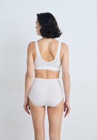 White cotton bralette and high-waisted brief, featuring a smooth texture, wide straps, and minimal seams, viewed from behind.