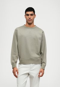 Světle zelená mikina vyrobená z měkké látky, s kulatým výstřihem, dlouhými rukávy a žebrovanými manžetami a spodním lemem, s jemným strukturovaným vzorem.