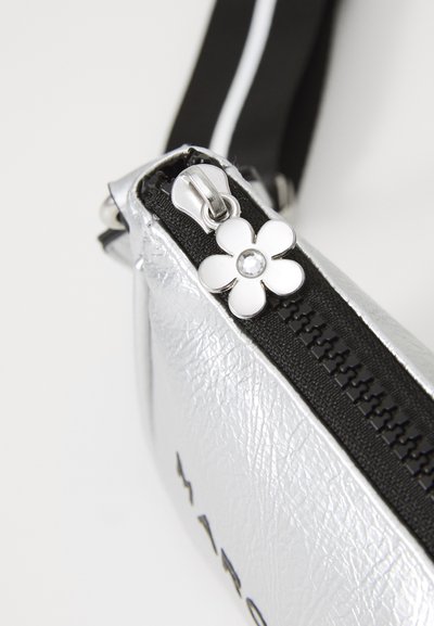 Sølv lærveske med en svart glidelås og en dekorativ sølvblomst-anheng med en rhinestone i midten. Kompakt og geometrisk form.