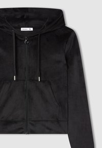 Felpa nera corta realizzata in tessuto morbido e testurizzato. Presenta una chiusura con zip, tasche frontali e coulisse regolabile con punte in argento.