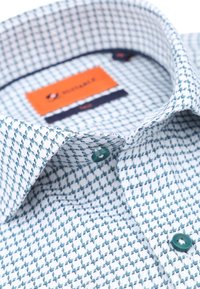 Katoenen shirt met een geometrisch blauw-wit patroon, voorzien van een gespreide kraag en groene knopen. Etiket zichtbaar met merknaam.