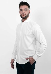 Witte overhemd met een klassieke kraag en lange mouwen, gemaakt van gladde stof, met een afgeronde zoom en zonder zichtbare patronen.