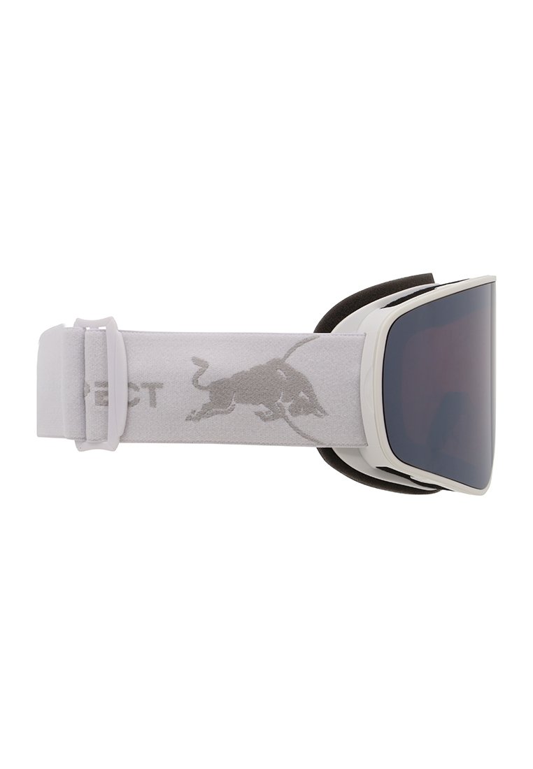 Des lunettes de ski avec une monture blanche, des verres teintés foncés et une sangle grise arborant un logo de taureau rouge. Rembourrage doux le long de la monture intérieure.