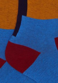 Calze con una base blu e sezioni arancioni e bordeaux; texture liscia con motivi a contrasto e dettagli nel tallone rinforzato.