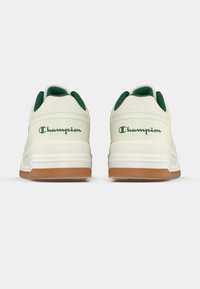 Λευκά αθλητικά παπούτσια με πράσινες λεπτομέρειες και γλώσσα από δίχτυ. Διαθέτουν λαστιχένια εξωτερική σόλα και λογότυπο "Champion" στη φτέρνα.