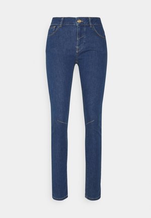 Jeans ajustados en denim azul oscuro, con una alta cintura, bolsillos delanteros y botón dorado. Textura lisa con detalles de costura sutil.