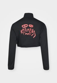 Black cropped jacket featuring a high collar and long sleeves. The back displays pink graphic text and designs. ح