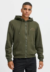 Felpa zip a collo alto di colore verde scuro, realizzata in tessuto morbido, con cappuccio regolabile, tasche frontali e un logo discreto sul petto.