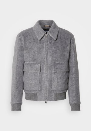 Gray herringbone-patterned jacket with a collar, front zipper, and two flap pockets. Features ribbed cuffs and hem for fit.