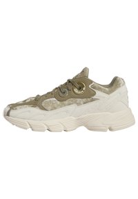 Ljusbeige sneakers med en blandning av slät syntet och texturerad mocka, med en framträdande grön accent och logodetalj.