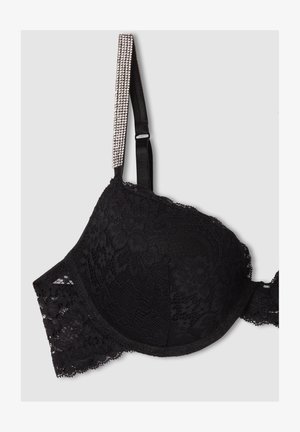 Reggiseno nero in pizzo con coppe imbottite, motivo floreale e un delicato bordo in pizzo. Spallina decorata con scintillanti strass.
