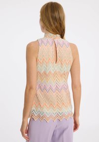 Ärmelloses Oberteil im mehrfarbigen Zickzackmuster mit einem Schlüsselloch-Design auf der Rückseite, hergestellt aus leichtem Stoff mit strukturierter Oberfläche und gewelltem Saum.