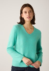 Minzgrüner Strickpullover mit V-Ausschnitt, langen Ärmeln, strukturiertem Rippstrick und entspannter Passform, mit einer vertikalen Nahtdetail an der Vorderseite.
