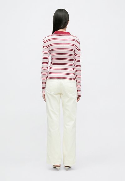 Chemise à manches longues rayée rouge et blanc avec col, associée à un pantalon large crème. Texture lisse et coupe ajustée.