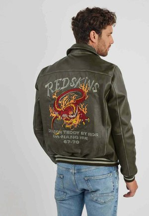 Veste en cuir vert olive avec une broderie de dragon en rouge et orange dans le dos, munie de poignets et d'un ourlet côtelés, ainsi que du texte "REDSKINS".