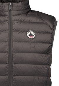 Chaleco acolchado sin mangas de color gris oscuro con cremallera frontal y parche redondo con logo que muestra un scooter y el texto "Just Over The Top JOTT".