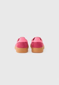 Lyserøde sneakers med overdel i ruskind og syntetiske materialer, gummisål, polstret krave og rundt tådesign. Teksturerede detaljer giver greb.