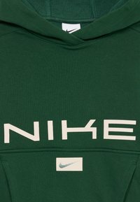 Mørkegrønn hettegenser med stor hvit Nike-tekst over brystet og et lite rektangulært merke med Nike-svingen logo under.