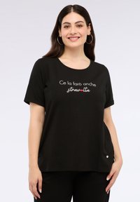 Camiseta negra de manga corta con cuello redondo, que presenta texto bordado en blanco y rojo. Tejido suave, corte holgado, pequeño detalle de logo en el lateral.