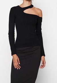 Schwarzes Langarmtop aus geripptem Stoff mit asymmetrischem Ausschnitt und einem Cutout an der linken Schulter. Glatte Textur, figurbetontes Design.