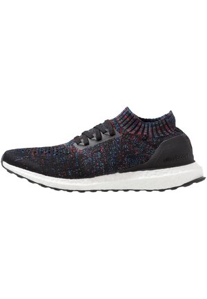 Chaussure de sport en maille noire avec des taches multicolores. Comprend un col montant, un design à lacets et une semelle blanche Boost pour l'amorti.