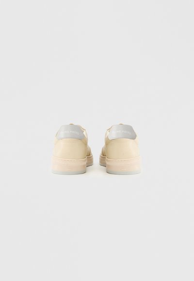 Beezh/värvi spordijalatsite paar, millel on heledalt hallid kandmise ribad "Filling Pieces" logoga, tagantvaates valgel taustal.