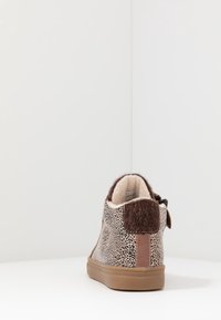 Hnědé tenisky na vyšší podrážce s animal print vzorem, s béžovou gumovou podrážkou, měkkým vnitřkem a texturovaným hnědým zadním poutkem.