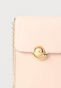 Rózsaszín bőrtáska arany kör alakú kapoccsal, patenttal és láncos pánttal. Simas textúra és finom varrási részletek.