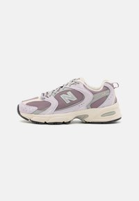 Adidași New Balance 530, cu un design din suede și plasă în nuanțe de mov pastel, accente bej și o talpă confortabilă cu un știft din cauciuc negru texturat.