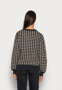 Pull en maille avec motif tissé beige et bleu marine, col rond, manches longues et ourlet texturé.