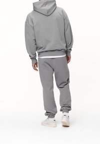 Felpa grigia e pantaloni abbinati realizzati in materiale morbido. La felpa ha una vestibilità comoda e polsini a costine, con caviglie elastiche sui pantaloni.
