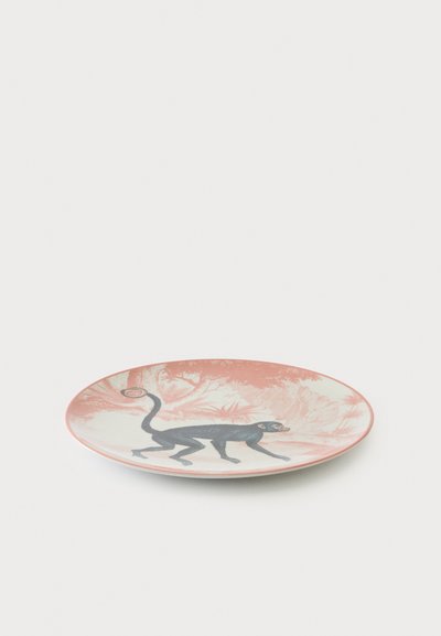 Assiette ronde en céramique avec un fond rose et blanc présentant une illustration d'un singe noir en position de marche.