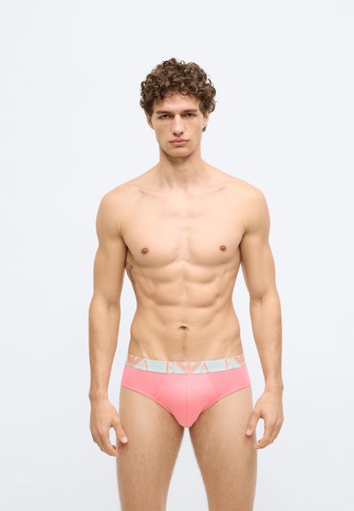 Cuecas justas para homem em tecido cor de rosa claro, com uma cintura elástica com logo em cinza claro contrastante. Textura suave, design minimalista.