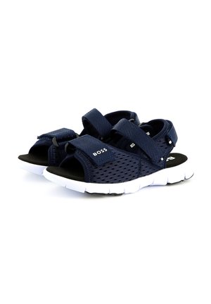 Marineblauwe mesh-sandalen met verstelbare klittenbanden, gesteunde zwarte binnenzool en witte rubberen buitenzool met een gestructureerde rand.
