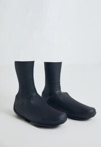 Musta vedenpitävä nilkkakengät, joissa on saumatonta muotoilua, venyvä päällismateriaali ja teksturoitu kumipohja. Kevyet ja istuvat.