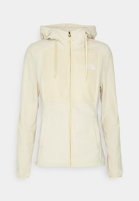 Chaqueta con capucha beige y cremallera, con un acabado texturizado, que presenta un logo blanco en el lado izquierdo del pecho, dos bolsillos frontales y cordones ajustables.