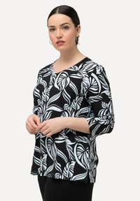 Černobílý top s listovým vzorem, výstřihem do V a tříčtvrtečními rukávy. Vyrobeno z lehkého materiálu s volným střihem.