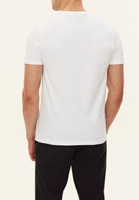 T-shirt bianca a maniche corte con scollo rotondo classico, texture liscia e vestibilità comoda, vista da dietro.