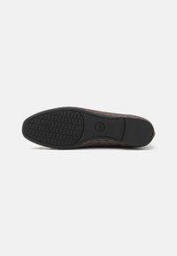 Braun gemusterter Schuh mit einer strukturierten Gummisohle. Das Obermaterial weist ein gewebtes Design auf, während die Sohle ein markantes Grippmuster hat.