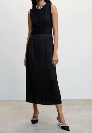 Schwarzes Midikleid mit vertikalen Falten, ärmellosem Design, rundem Ausschnitt und taillierter Passform. Akzentuiert mit einer auffälligen silbernen Halskette.