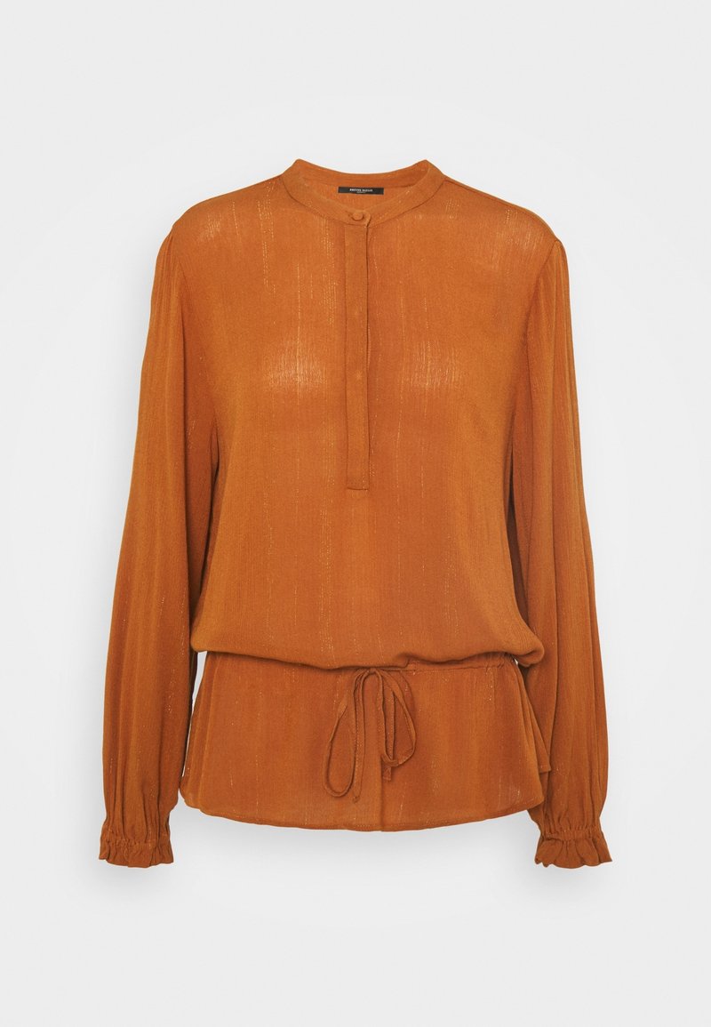 Blouse à manches longues couleur rouille avec petit col montant, patte de boutonnage, taille à cordon de serrage et poignets élastiques.