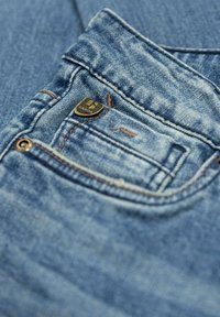 Jeans de mezclilla en un color azul deslavado, con costuras en contraste y un pequeño botón metálico de la marca en el bolsillo trasero.