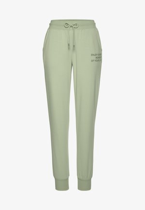 Hellgrüne Sweatpants mit einem Kordelzugbund, seitlichen Taschen und gerippten Bündchen. Präsentiert bedruckten Text auf dem linken Oberschenkel.