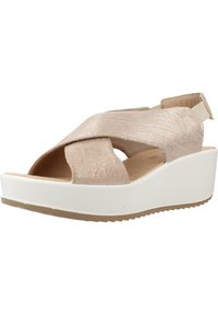 Beige klínové sandály s křížovými řemínky. Měkký texturovaný materiál, otevřená špička a elastický pásek na zadní straně. Bílý platformový základ s protiskluzovou podrážkou.